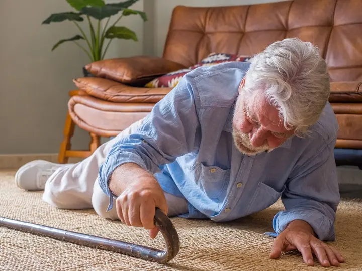 elder-senior-man-lying-floor-after-falling-down-with-wooden-walking-stick-beside-couch-rug-living-room-home-old-man-suffering- Időskori csonttörések megelőzése tápanyagokkal Szupertápanyagok 