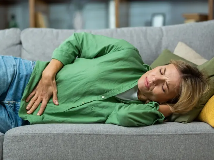 mature-woman-alone-home-sick-holding-hands-side-stomach-having-severe-spasm-lying-sofa Ételmérgezés: tünetei, megelőzés és teendők Emésztés 