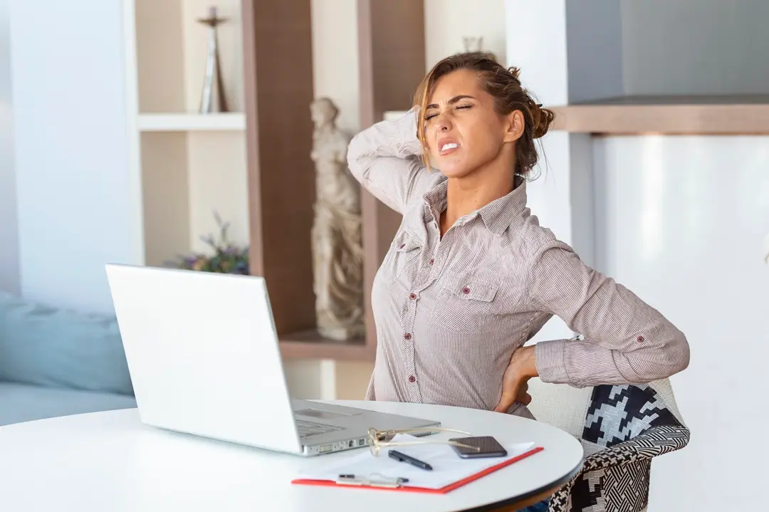 portrait-young-stressed-woman-sitting-home-office-desk-front-laptop-touching-aching-back-with-pained-expression-suffering-from-backache-after- Természetes gyulladáscsökkentők ülőidegzsábára Ízületek és izmok 
