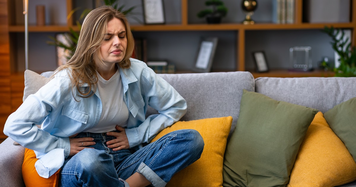 portrait-woman-with-stomach-ache-sitting-sofa-holding-hands-her-stomach Gyomorégés: okai, tünetei és természetes enyhítése Emésztés 